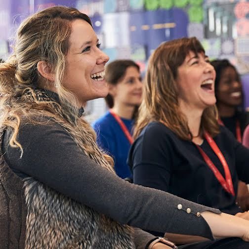 2 women at conference, laughing.